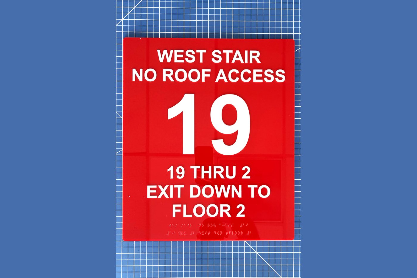 Red stair identification sign reading West Stair No Roof Access, floor 19, exit down to floor 2, with Braille