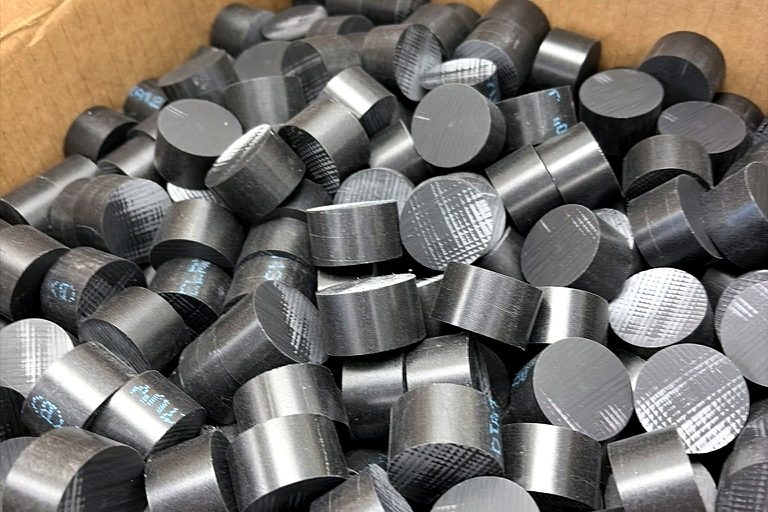 Box of black Delrin acetal rod cut into pucks