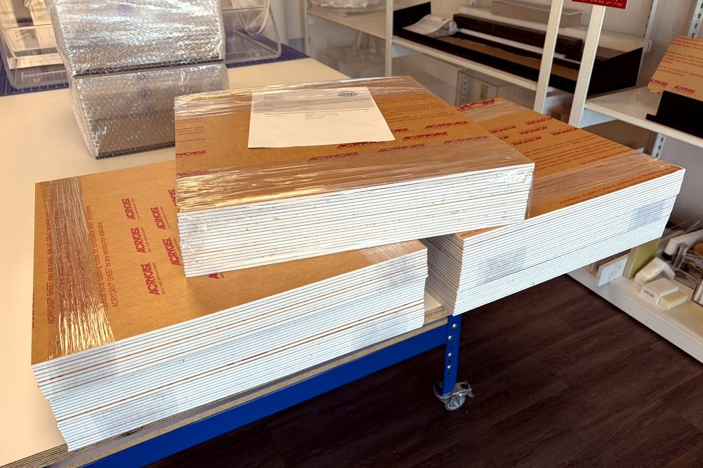 Stacks of white cast acrylic cut to size and wrapped for pickup