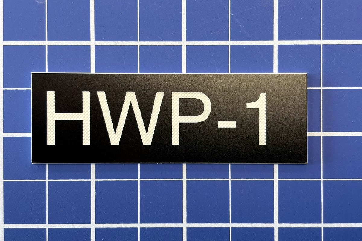 Black and white laser-engraved equipment identification tag reading HWP-1