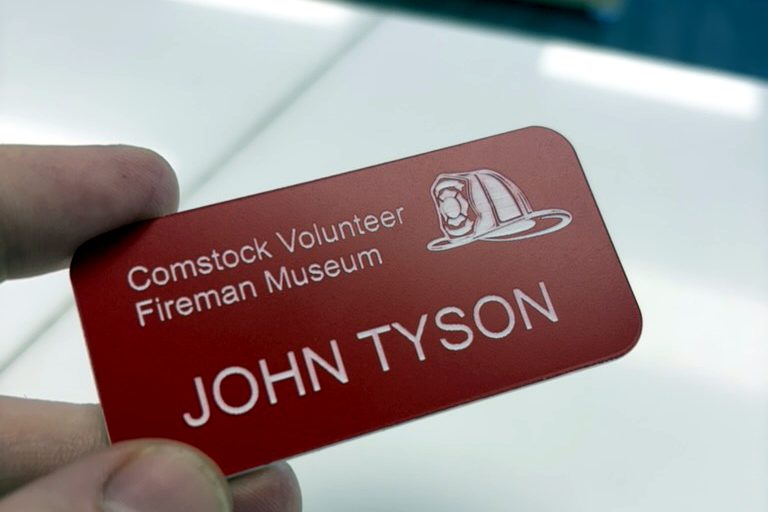 Red laser-engraved name badge with logo for a museum volunteer