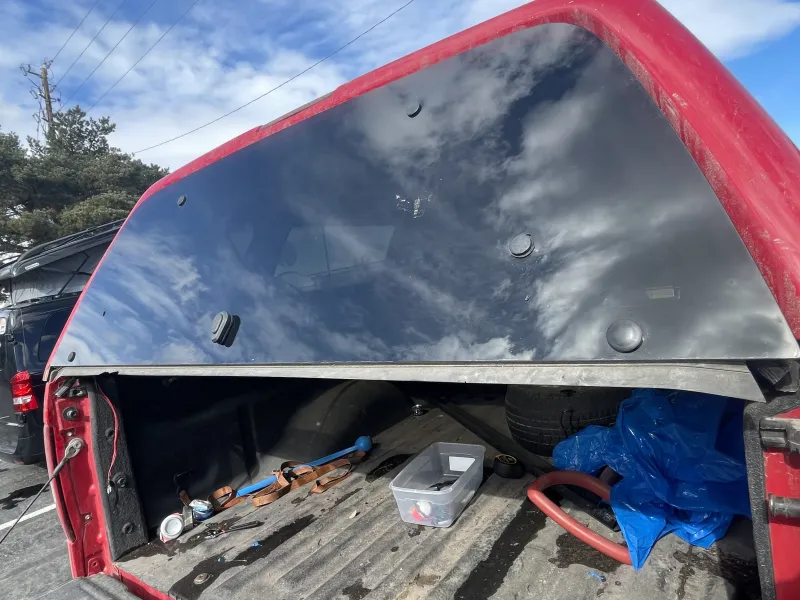 Open truck bed with scattered tools and tire.