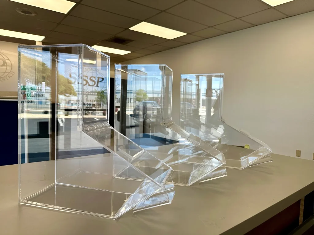 Clear plastic display cases on a table in office.