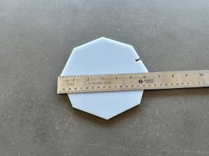 Octagon-shaped object measured with ruler on gray surface.
