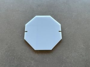 White octagonal plastic piece on gray surface