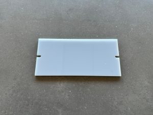 White plastic card with notches on gray surface